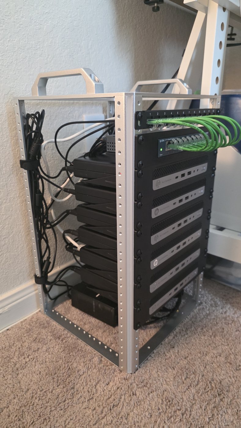 The rack seen from an angle, with the six power bricks and their cabling hanging in the space behind the mounted nodes.