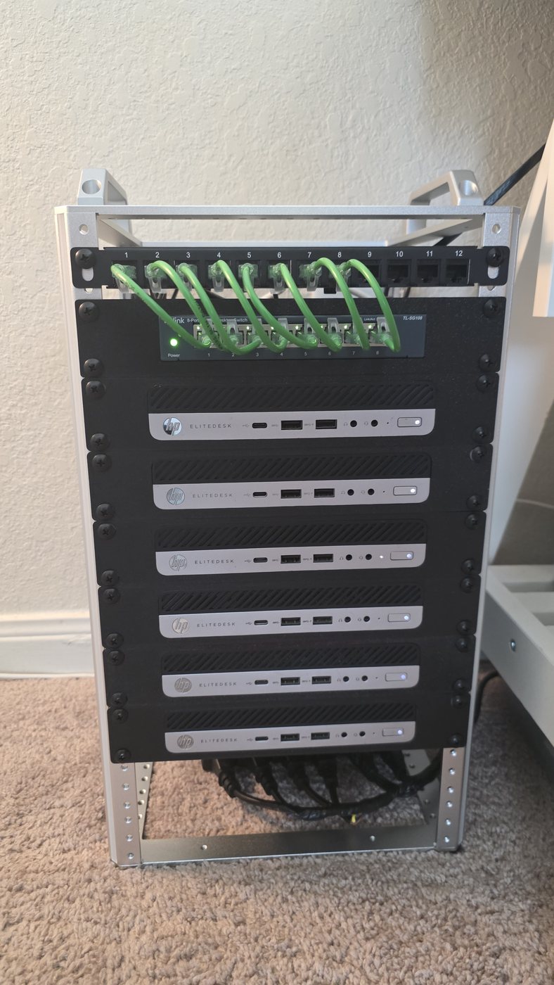 Six HP EliteDesk 800 G3 mini PCs stacked in an open desktop rack with a patch panel and an eight-port switch above them.